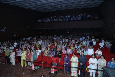 The whole hall standing, the balcony packed above rows of red seats.