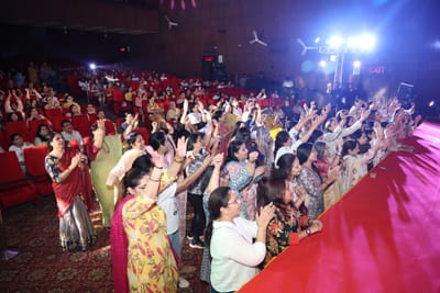 The audience standing along the red edge of the stage, clapping and singing.
