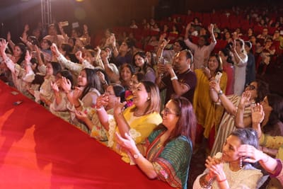 The front row clapping with hands lifted, laughing as they sing.