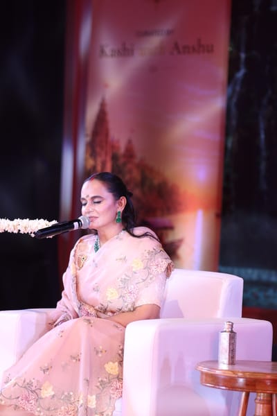 Anshu singing with her eyes closed at the jasmine-wrapped microphone.