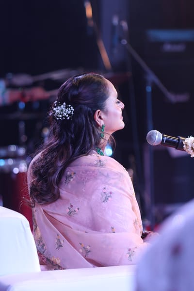 Anshu with her head bowed at the microphone at the end of a bhajan.