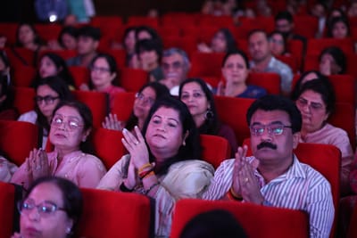 The audience applauding with hands folded and raised, filling the red seats.