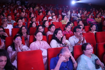 Rows of the audience applauding from the red seats, close enough to read the faces.